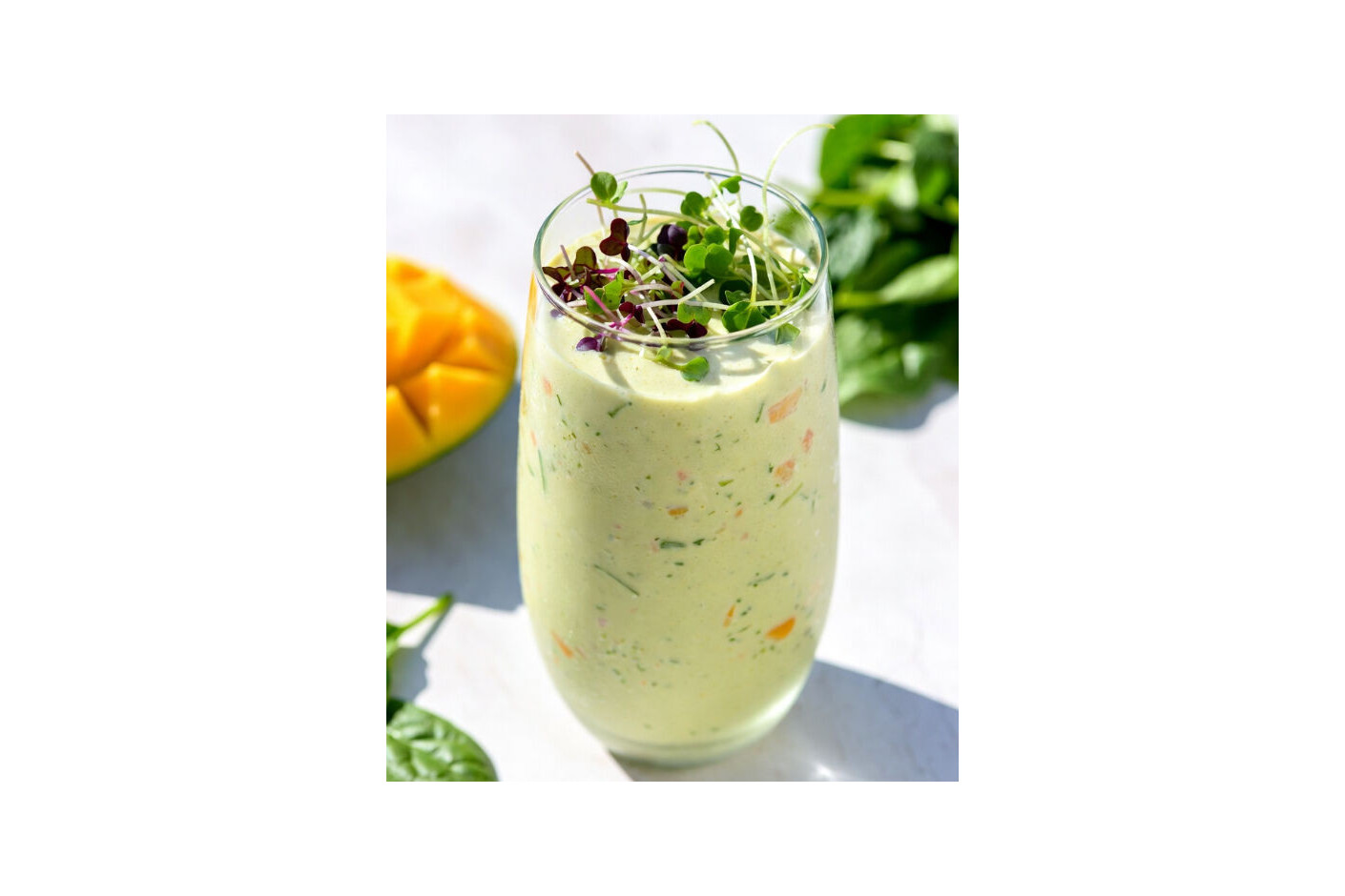 Smoothie verde cremoso con mango y microgreens Mikagreens de hierba de trigo, melisa limón y amaranto rojo